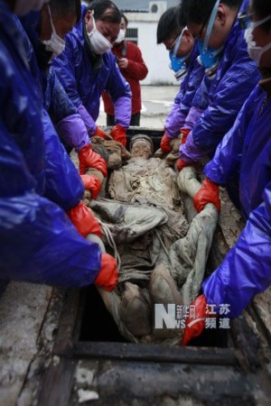 江苏省泰州市博物馆工作人员将明代不腐女尸抬出棺外