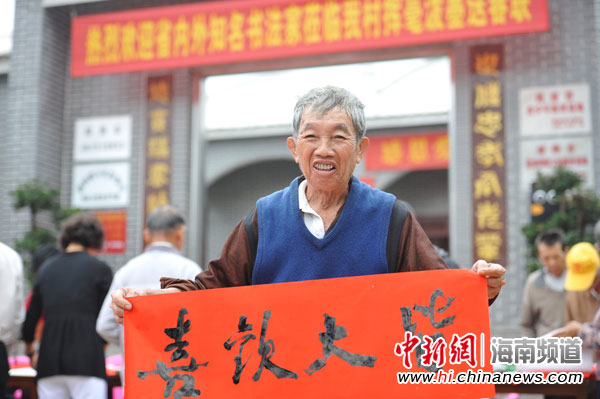一位村民高兴地展示书法家写的春联横批。